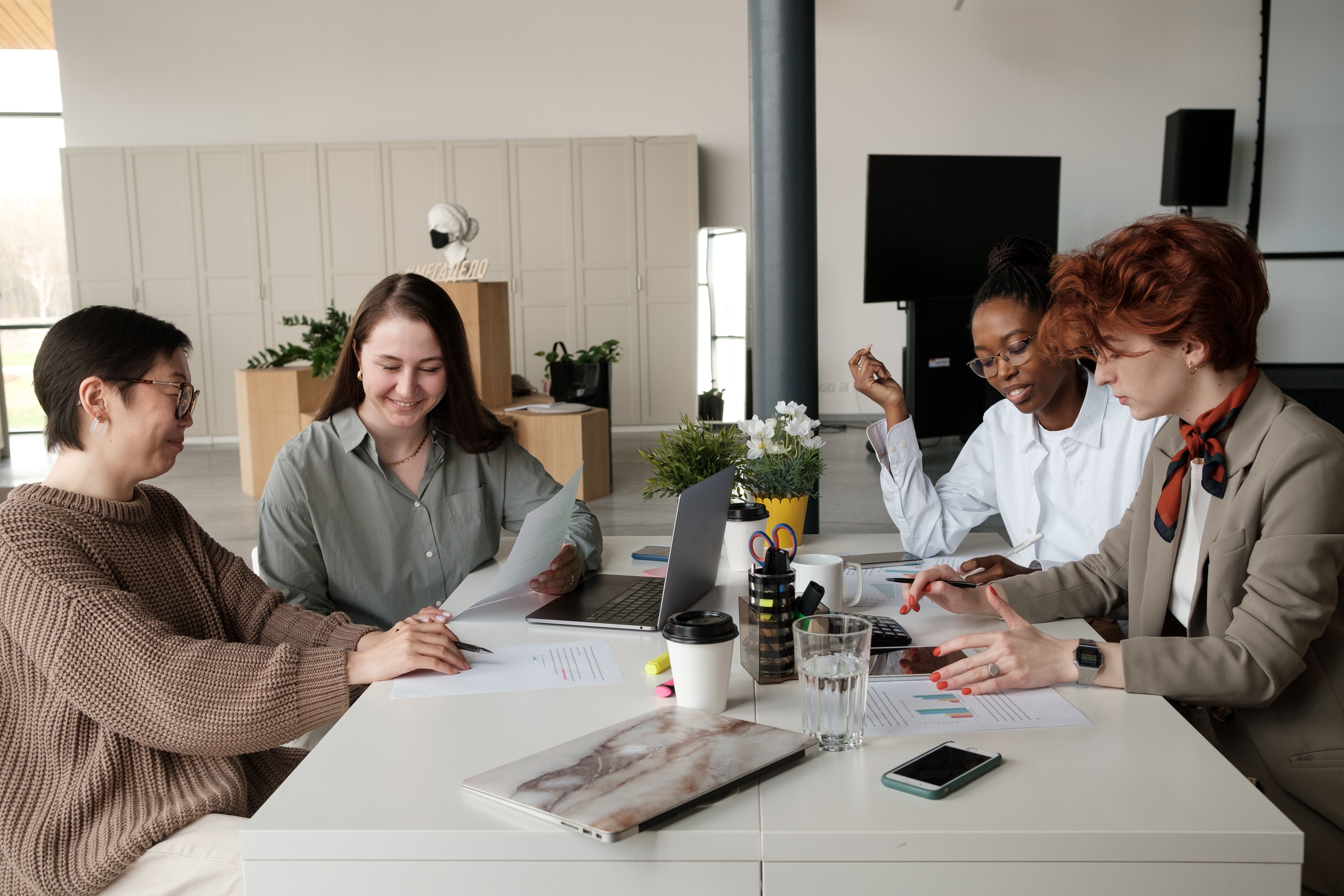 Four professionals smiling and collaborating around a table
